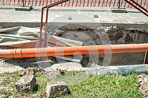 Open trench on the street excavation site with visible pipes for water gas and district heating pipeline system in the urban city