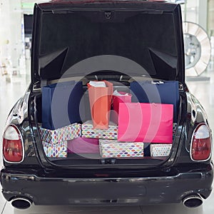 The open trunk of a car is filled with shopping bags from the mall. Holiday shopping.