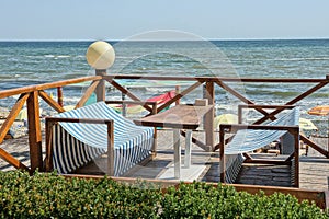 Open veranda of the restaurant with a wooden table and seats with striped fabric