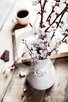 Open vintage book with blossom branch of cherry-tree on wooden table with a beautiful vintage vase