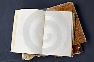 Open vintage book in a super cover on a stack of old dilapidated books