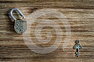 Open vintage padlock and key on a wooden texture