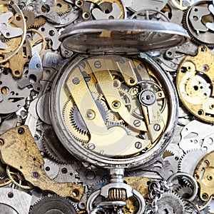 Open vintage pocket watch on pile of spare parts