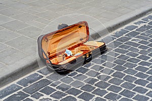 Open violin case lies on an old cobblestone in the city. Street musician collects money