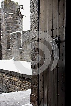Open vointage wooden door in medieval castle. Narrow wooden entrance to castle yard with brick walls. Winter view open door.