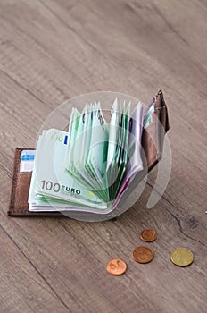 Open wallet with euro currency on the wooden table