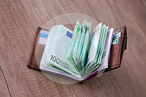 Open wallet with euro currency on the wooden table