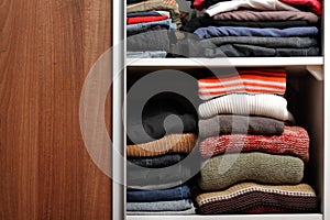 Open wardrobe with lots of folded clothes