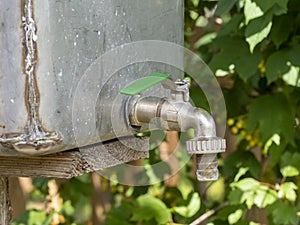 Open water faucet or tap with flowing water in blur garden background