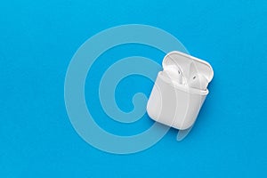 An open white box with white wireless headphones on a blue background