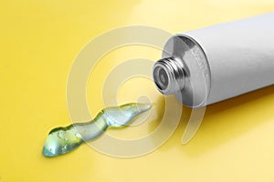 Open white tube with ointment on yellow background, closeup