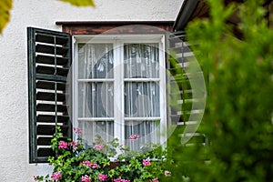 Open Window on the Facade of a white local traditional old House decorated with flower in a European style at countryside village