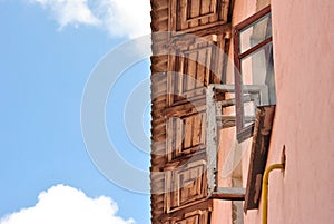 Open window in an old wooden frame under the roof and blue sky