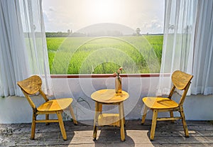 The open windows let the sunlight into the room where tables and chairs with vases of flowers were placed