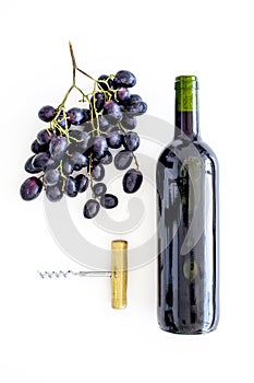 Open the wine concept. Red wine in glass bottle near bunch of grapes and corkscrew on white background top view