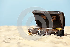 Open wooden chest with treasures on sandy beach, space for text