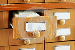 Open wooden drawer analogue paper filing cabinet with blank sticker slips. Vintage information repository in a university or