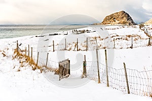 Open wooden gate on a snowy beach.