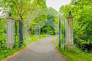 Open wrought iron gate between two stone pillars