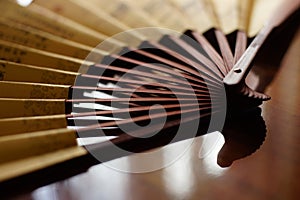 Open yellow fan with brown chinese characters on the table, closeup, side view