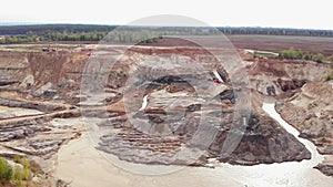 Opencast mining quarry with lots of machinery. Iron ore quarry from bird`s eye view. Open pit for gold mining. Open pit mine coal