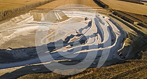 Opencast mining quarry with machinery at work - Aerial view. Industrial Extraction of lime, chalk, calx, caol