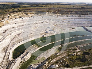 Opencast mining quarry with machinery at work - Aerial view. Industrial Extraction of lime, chalk, calx, caol. View from above