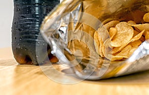 Opened Bag of Potato Chips with a Bottle of Soft Drink in the Background