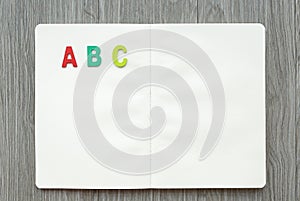 Opened blank book with letters ABC on wood table. Education concept