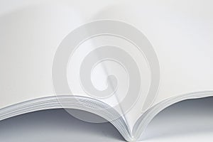 Opened blank magazine with white pages on white background and close-up selective view