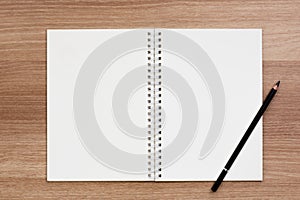 Opened blank ring spiral binding notebook with a pencil on wooden surface