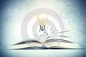 The opened book with alphabet letter flying out with glowing light bulb of pages , education and knowledge concept, vintage color