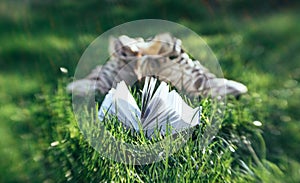 Opened book on the background of green lawn and old shoes