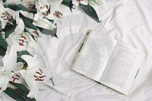 An opened book on the bed. Flat lay
