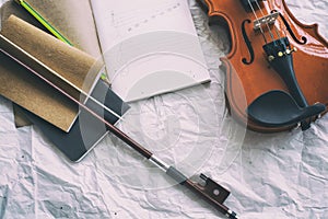 The opened book with drawing note put at the middle of half front side of violin and bow