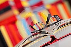 Opened book and glasses on colored background