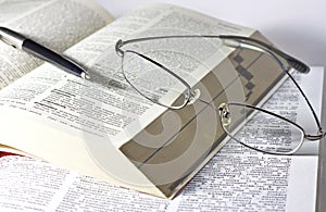 Opened book, pen and glasses
