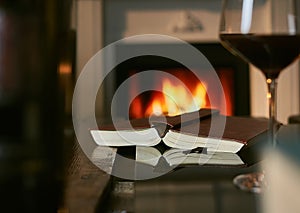 Opened book and red wine on table with fireplace in the background