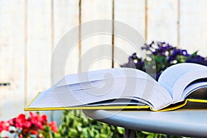 Opened book on table in flower garden