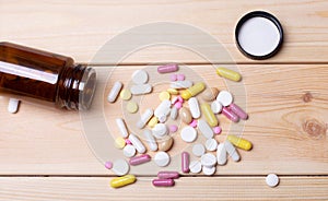 Opened bottle of pills with multicolored pills on a wooden background. Medical concept. Pharmaceuticals