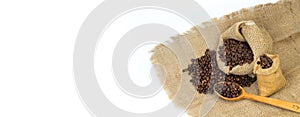 Opened burlap bags, a cup of coffee, scattered whole coffee beans on a white background. Banner