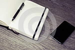 Opened calendar or diary with pen and cellphone on wooden table