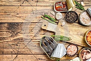 Opened cans conserve with saury, salmon, sprats, sardines, squid and tuna. Wooden background. Top view. Copy space