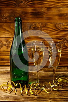Opened champagne bottle and two glasses of champagne on wooden table
