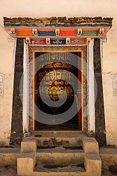 Opened colorful door with buddhist praying instrument inside the room with ancient scripts on it