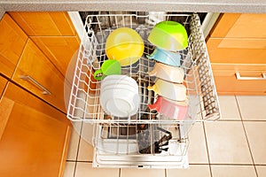 Opened dishwasher with crockery in it`s rack photo