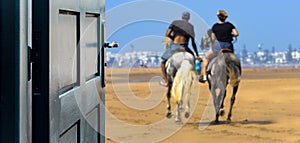 Opened door concept with a couple of rider on the beach on a blurred background