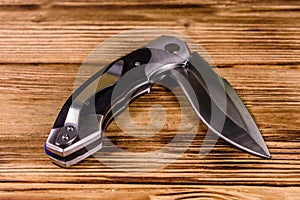 Opened folding knife on a wooden table