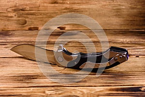 Opened folding knife on a wooden table