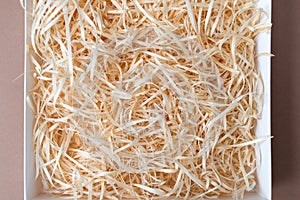 Opened gift box with decorative straw, filler, shavings.